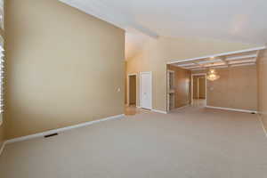 Carpeted living/dining room with a chandelier and beamed ceiling