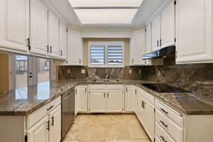 Kitchen with black electric stovetop, backsplash, sink, dishwasher, and white cabinetry