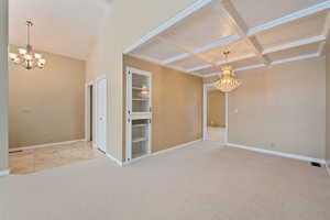 Entryway and dining area room featuring beamed ceiling, light carpet, a notable chandelier, and coffered ceiling