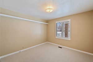 Carpeted bedroom 2 with a textured ceiling