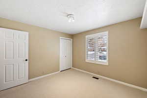 Bedroom 3 with a textured ceiling, light colored carpet, and a closet