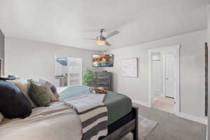 Carpeted bedroom with ensuite bath and ceiling fan