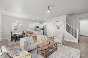 Living room with light hardwood / wood-style floors and ceiling fan with notable chandelier