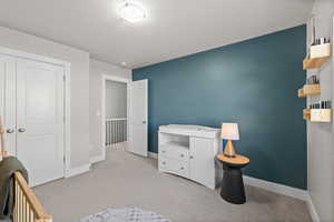 Bedroom featuring light colored carpet, a textured ceiling, and a closet