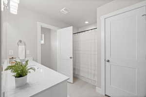 Bathroom with a shower with curtain and vanity