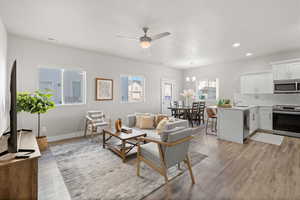 Living room with a wealth of natural light, sink, light hardwood / wood-style floors, and ceiling fan with notable chandelier