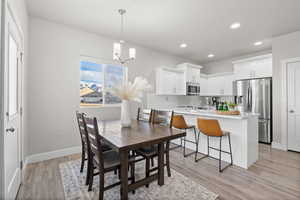 Dining area featuring sink, light hardwood / wood-style floors, and a notable chandelier