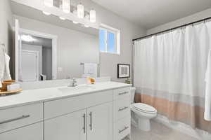 Full bathroom with shower / bath combination with curtain, vanity, and toilet