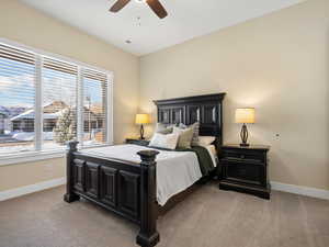 Carpeted bedroom featuring multiple windows and ceiling fan