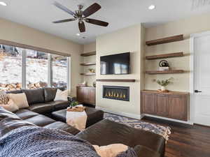 Living room featuring ceiling fan, built in features, and dark wood-type flooring