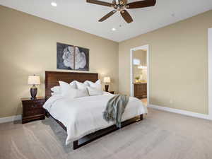 Bedroom featuring light carpet, ensuite bathroom, and ceiling fan