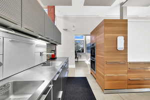 Kitchen with light tile patterned floors, sink, and double oven