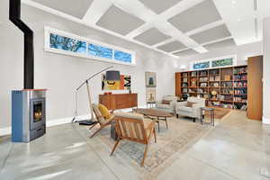Living room with a wood stove, a towering ceiling, and concrete floors
