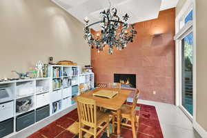 Dining space with a tile fireplace, an inviting chandelier, and tile walls