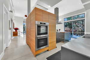 Kitchen featuring a wealth of natural light, a center island, double oven, island exhaust hood, and gray cabinets
