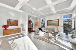 Living room with light tile patterned flooring, a wealth of natural light, and coffered ceiling