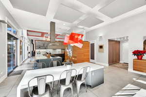 Kitchen featuring a breakfast bar, island range hood, kitchen peninsula, and light tile patterned floors