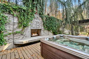 Wooden terrace featuring exterior fireplace and a hot tub
