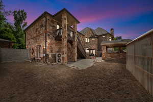 Back house at dusk featuring a patio area and a balcony