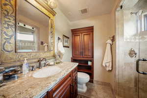 Bathroom featuring vanity, toilet, and a shower with door