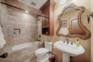 Full bathroom with sink, tiled shower / bath combo, and toilet