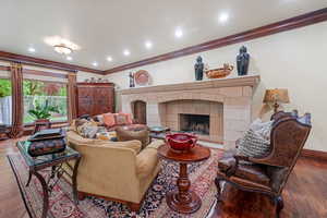 Living room with hardwood / wood-style floors, ornamental molding, and a tile fireplace