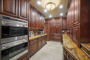 Kitchen featuring light stone countertops, sink, and double oven