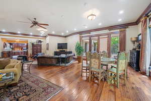 Dining space featuring wood-type flooring, french doors, ceiling fan, and ornamental molding