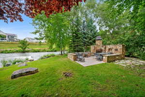 View of yard featuring a patio area and an outdoor stone fireplace