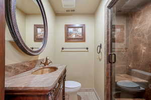 Bathroom with vanity, toilet, and a shower with shower door