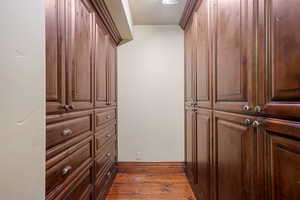 Walk in closet with dark hardwood / wood-style floors