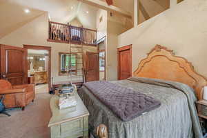 Bedroom featuring light carpet, connected bathroom, and high vaulted ceiling