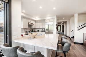 Kitchen with stainless steel built in fridge, light hardwood / wood-style flooring, decorative backsplash, kitchen peninsula, and a breakfast bar area