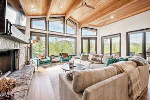 Sunroom featuring vaulted ceiling with beams, ceiling fan, a fireplace, and wooden ceiling