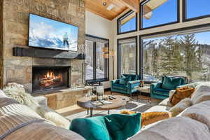 Living room with wood ceiling, a stone fireplace, beamed ceiling, and a wealth of natural light