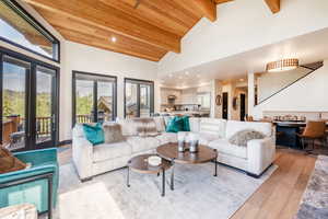 Living room featuring beam ceiling, light wood-type flooring, high vaulted ceiling, and wood ceiling