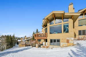 Snow covered rear of property with a deck