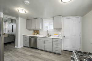 Kitchen with sink, range, stainless steel dishwasher, gray cabinets