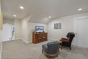 Sitting room with light carpet and vaulted ceiling