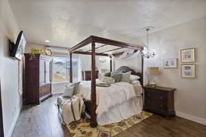 Bedroom with dark hardwood / wood-style flooring, a textured ceiling, and a notable chandelier