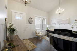 Foyer featuring dark hardwood / wood-style floors, vaulted ceiling, and a notable chandelier