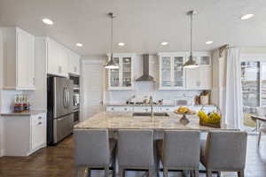 Kitchen with white cabinets, appliances with stainless steel finishes, and wall chimney range hood