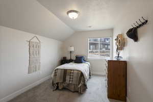 Carpeted bedroom featuring a textured ceiling and vaulted ceiling