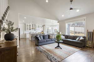 Living room with dark hardwood / wood-style floors, high vaulted ceiling, and ceiling fan