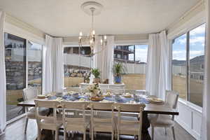 Dining room featuring a chandelier, wood-type flooring, and a textured ceiling