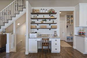 Bar with light stone countertops, dark wood-type flooring, a textured ceiling, decorative backsplash, and white cabinets