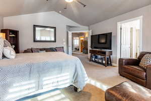 Carpeted bedroom featuring vaulted ceiling and ceiling fan