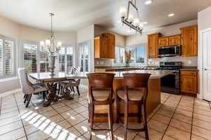 Kitchen featuring a center island, decorative light fixtures, light tile patterned flooring, stainless steel appliances, and a chandelier