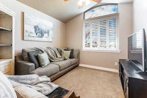 Living room featuring light colored carpet, vaulted ceiling, and ceiling fan