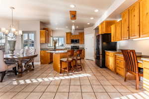 Kitchen featuring pendant lighting, a center island, an inviting chandelier, light tile patterned floors, and appliances with stainless steel finishes